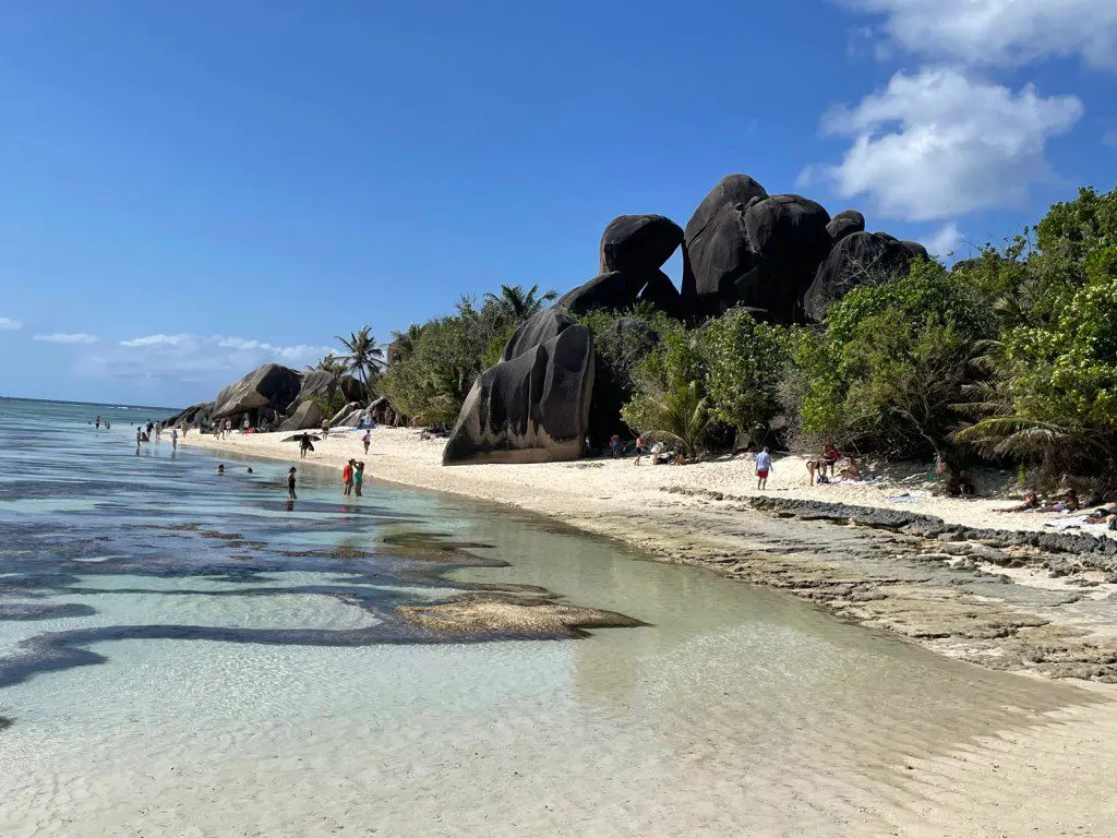 Strand Impression von La Digue - Strand, Palmen und Bäume, Meer, Felsen und Menschen 