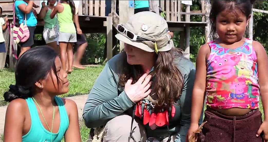 Paula knieend am Amazonas eingerahmt von zwei Mädchen 